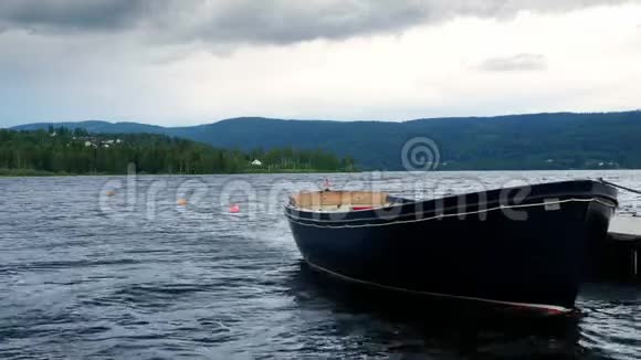 孤独的划艇系在漂浮的湖坞上在多云的天空下轻轻地在波浪中摇摆挪威阿克斯胡斯赫达尔附近视频的预览图