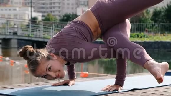年轻女子做瑜伽运动与城市背景埃卡帕达平衡姿势视频的预览图