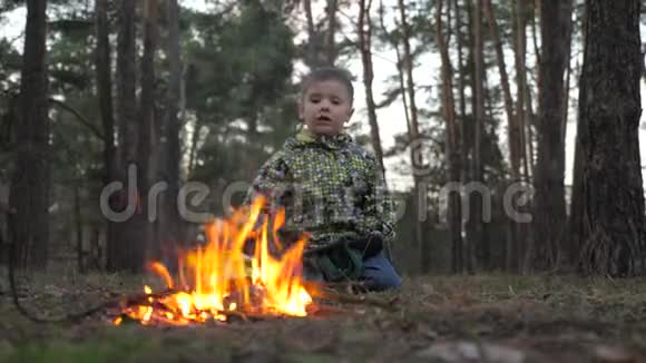 男孩盯着壁炉纵火背景漂亮的孩子在火里热身当战争来到家乡的时候难民视频的预览图