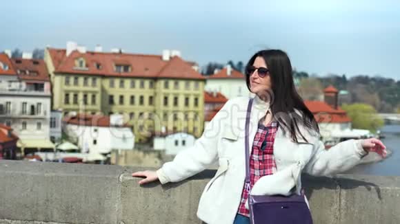 中镜头迷人的女游客微笑着放松地站在欧洲美丽的城市堤岸上视频的预览图