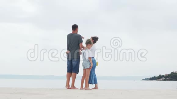夫妻可爱的年轻夫妇和他们的三个孩子在白沙滩上家庭旅行幸福的家庭度假视频的预览图