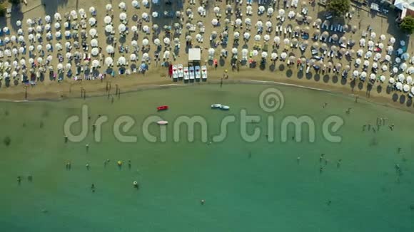 在一个炎热的阳光明媚的日子里鸟瞰海滩上挤满了人太阳伞站在黄色明亮的沙子里休息一下视频的预览图