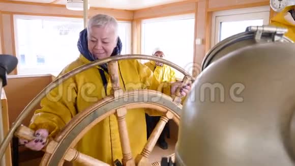 在帆船上的船长桥上一位老妇人转动方向盘成熟女船长掌舵漂浮视频的预览图