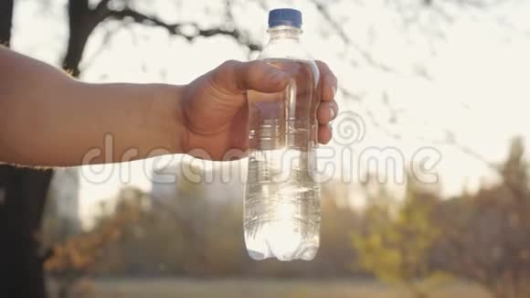 为另一个男人提供塑料瓶的白人男性特写运动员们在秋天的夕阳下共享水视频的预览图
