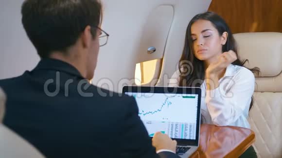 成功的女商人和商人乘坐私人飞机女人在看镜头男人为笔记本工作视频的预览图