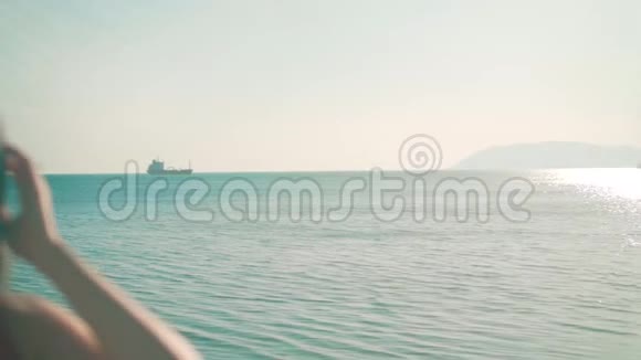一个穿着红色一件泳衣和眼镜的女孩站在海滨女孩摸了摸她的头发在风中吹起视频的预览图