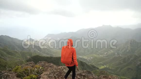 活跃的徒步旅行者女孩穿着橙色夹克欣赏阿纳加山脉加那利群岛特内里费一位和视频的预览图