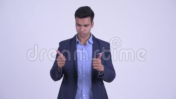 困惑的年轻印度商人在竖起大拇指和竖起大拇指之间做出选择视频的预览图