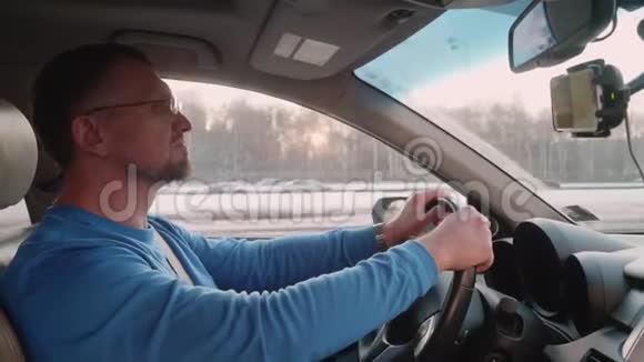 白色司机使用智能手机导航仪在高速公路上驾驶以检查道路下班后回家视频的预览图