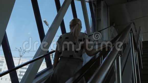 一个女人爬上商务中心或机场的自动扶梯视频的预览图