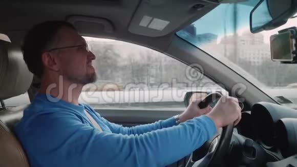 白人司机放慢速度让其他汽车通过男人微笑着对音乐点头日落的天空背光灯视频的预览图