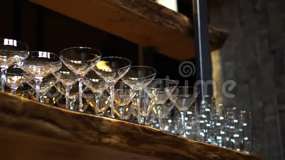 鸡尾酒杯排在木质阁楼风格的酒吧架子上视频的预览图