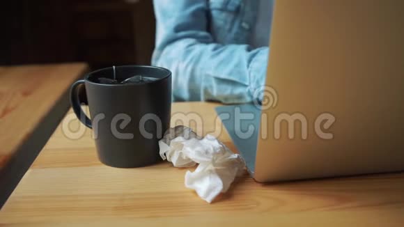 女人病了坐在咖啡馆里拿着笔记本电脑用手帕擦鼻涕视频的预览图