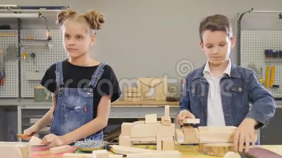 孩子们忙于在工艺车间玩耍可爱的小男孩和他的学龄妹妹玩木制半成品视频的预览图