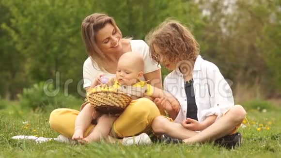 快乐的复活节家庭带着复活节篮子参加春季野餐一岁的孩子他妈妈和哥哥视频的预览图