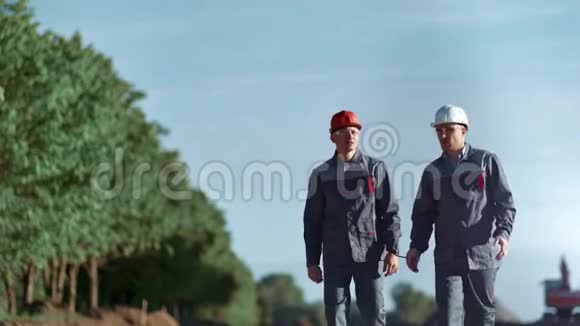 两名戴头盔穿工服的工人在户外中长距离行走视频的预览图