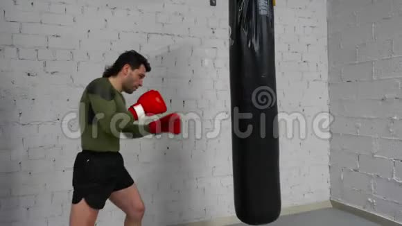 职业拳击手正在健身房训练练习用拳击袋进行踢打视频的预览图