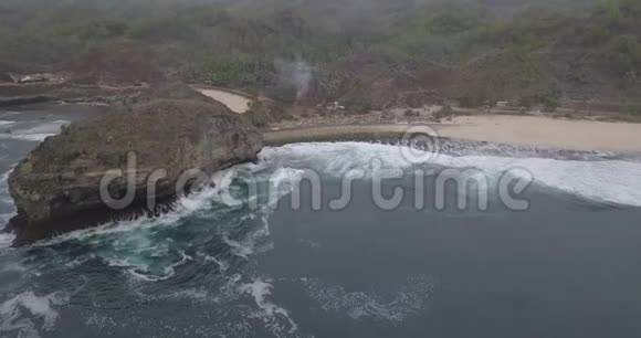 海浪拍打着礁石飞向白色沙滩山下有几棵椰子树视频的预览图