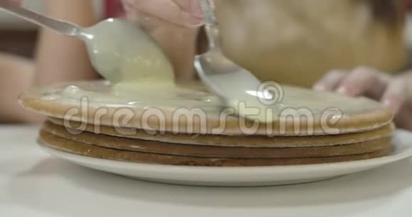 用浓缩牛奶涂抹烤蛋糕的勺子的极端特写盘子里有甜面包店电影4k镜头视频的预览图