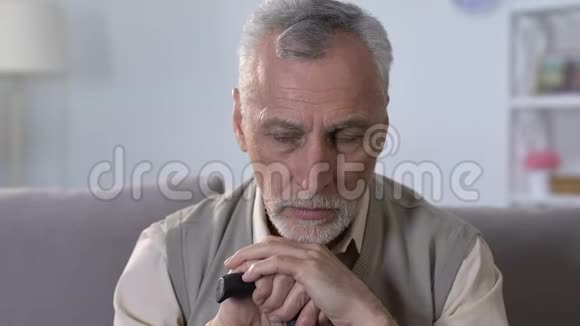 坐在康复中心沙发上的持手杖的忧郁老人视频的预览图