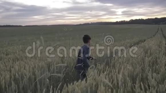 快乐的男孩穿过麦田在日落时欢欣雀跃视频的预览图