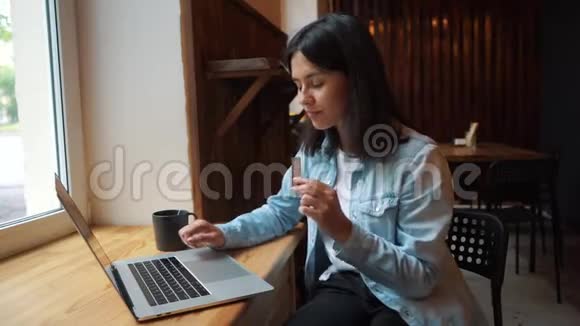 在笔记本电脑前的咖啡馆里吃巧克力的女孩视频的预览图