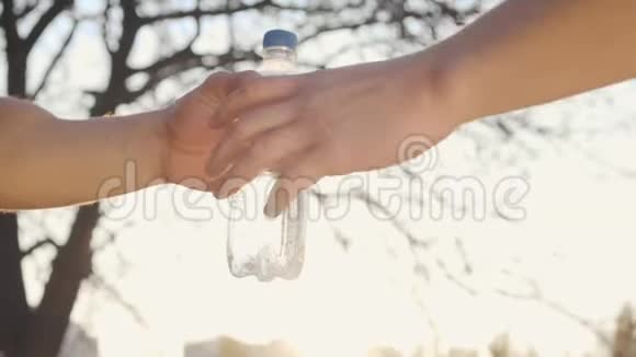 在秋天的公园里雄性白种人的手在日落时分享水两个成年男孩在阳光下握手视频的预览图