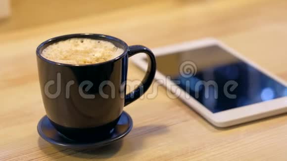 木制桌子上的数字平板电脑和咖啡杯视频的预览图
