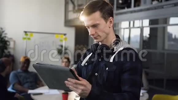 专注的商人在平板电脑上工作背景是一群年轻的商人视频的预览图