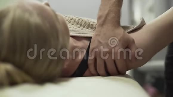 躺在按摩台上的年轻女性的男性手部按摩肩部的特写按摩治疗师的女孩视频的预览图