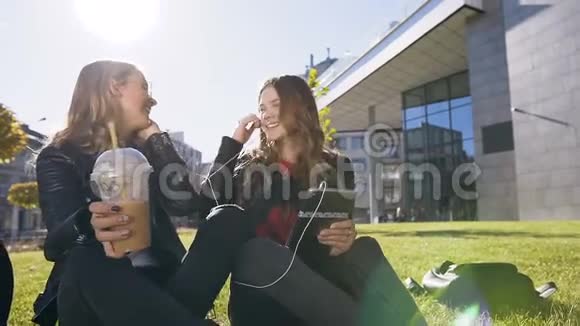 快乐的青少年朋友使用平板电脑坐在市中心公园的草坪上友谊视频的预览图