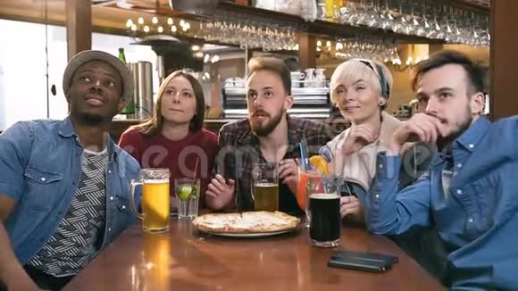 五个时髦的朋友喝啤酒喝鸡尾酒在酒吧为体育比赛加油视频的预览图