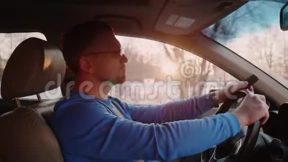 人驾驶汽车手里拿着按钮电话日落和穿过树木的阳光在背景上视频的预览图