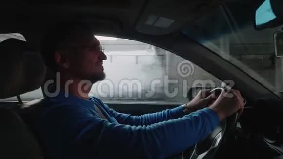 白人司机在天桥下开车微笑着向音乐点头冬季城市日落视频的预览图
