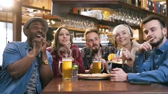 集中了五个年轻朋友在酒吧酒吧喝啤酒和鸡尾酒的时候看足球比赛视频的预览图