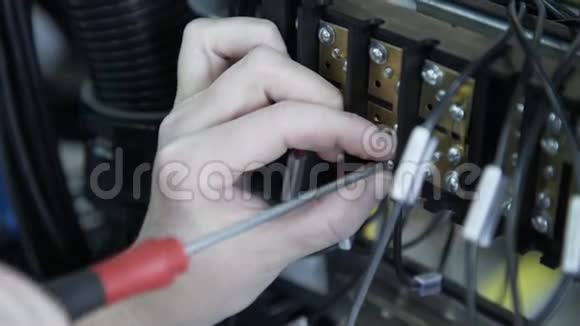工厂电工工程师用螺丝刀安装电缆将电子箱控制柜中的螺母拧紧到保险丝中视频的预览图