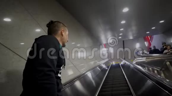 年轻的白种人在机场地铁的自动扶梯上移动视频的预览图