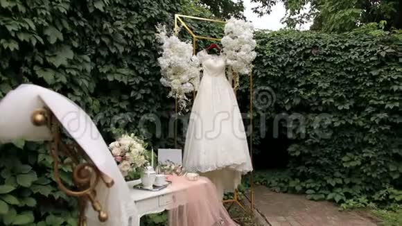 婚纱挂在华丽的婚礼拱门上上面覆盖着鲜花视频的预览图