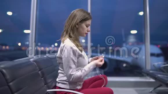 一位年轻漂亮的休闲女士的机场候机楼里做瑜伽冥想背景是飞机视频的预览图