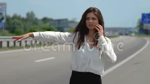 一位年轻漂亮的黑发女人试图在路上不再路过汽车看上去绝望了视频的预览图