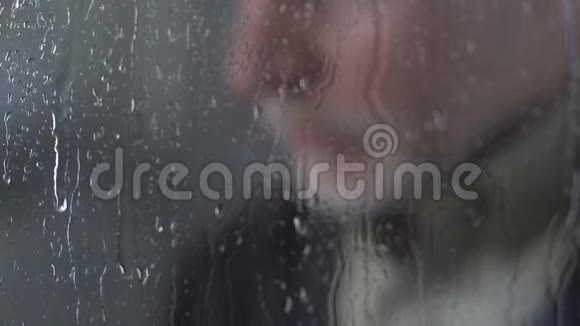 成熟的孤独的人沉重地站在雨窗旁望着外面视频的预览图