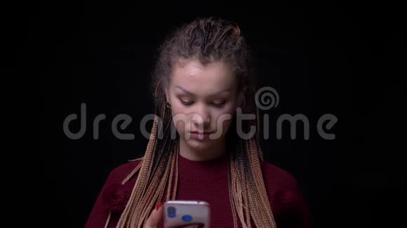 特别的黑发女孩与可怕的目光关注智能手机集中在黑色背景视频的预览图