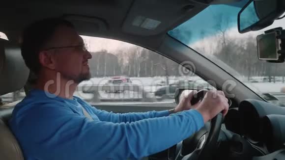 白人司机在繁忙的道路和不同汽车的交通中开车冬天的日落视频的预览图