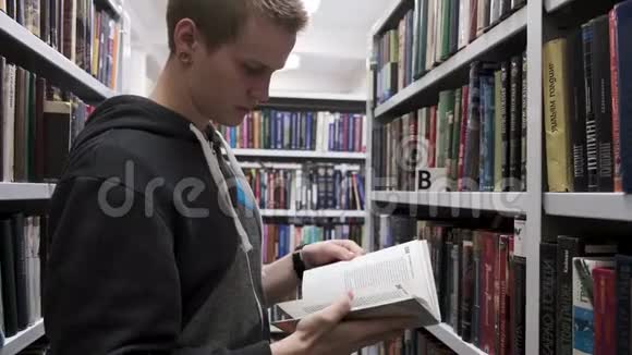 一个书店里的年轻人手里拿着一本打开的书手里拿着其他书架上面写着背景教育和视频的预览图