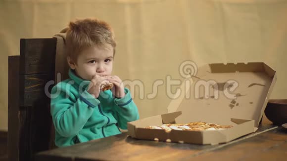 穿绿色毛衣的男孩坐在木椅上吃披萨美味的披萨小男孩拿着一片比萨饼视频的预览图