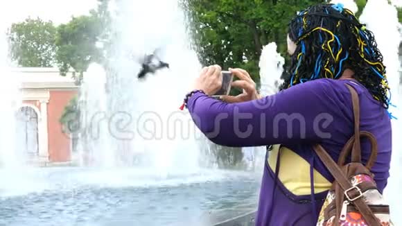 资深成年女性旅行者用她的智能手机拍摄关于美丽喷泉的照片或视频视频的预览图