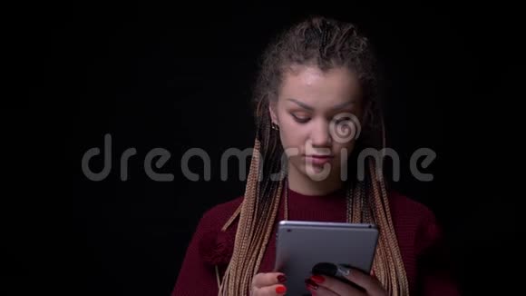 特别的黑发女孩与可怕的目光关注平板电脑集中在黑色背景视频的预览图