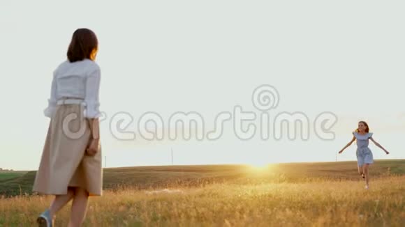 女孩跑去见她的母亲和拥抱妈妈和她的女儿在日落时在湖边视频的预览图