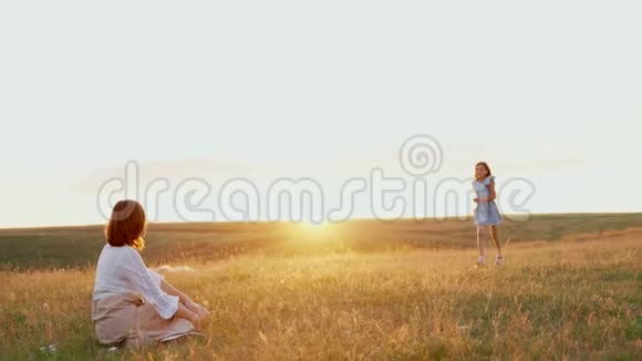 女孩跑去见她的母亲和拥抱妈妈和她的女儿在日落时在湖边视频的预览图