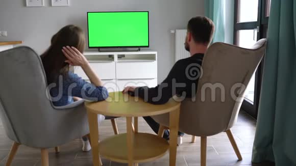 男人和女人坐在椅子上用绿色的屏幕看电视讨论他们看到了什么并用视频的预览图